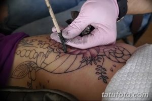 Фото процесса нанесения цветочной татуировки, демонстрирующее работу мастера и детализацию рисунка на коже.